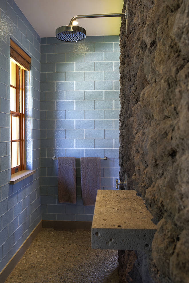 Exotisk inredning av ett badrum, med glaskakel, blå kakel, klinkergolv i småsten och beiget golv