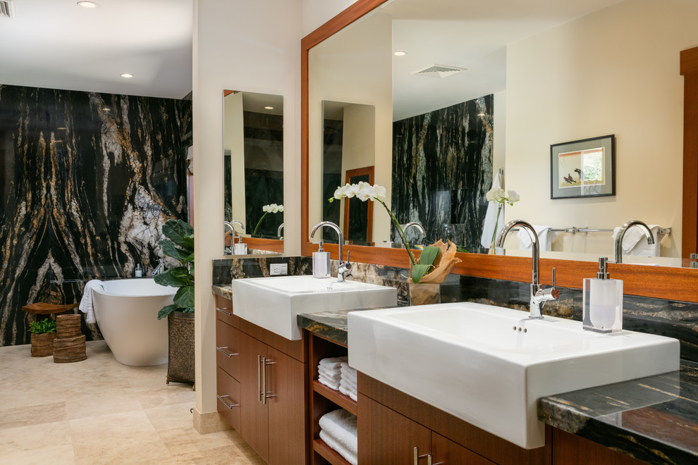 Bild på ett tropiskt en-suite badrum, med släta luckor, skåp i mörkt trä, ett fristående badkar, flerfärgad kakel, beige väggar, beiget golv, klinkergolv i keramik, bänkskiva i kalksten och ett avlångt handfat