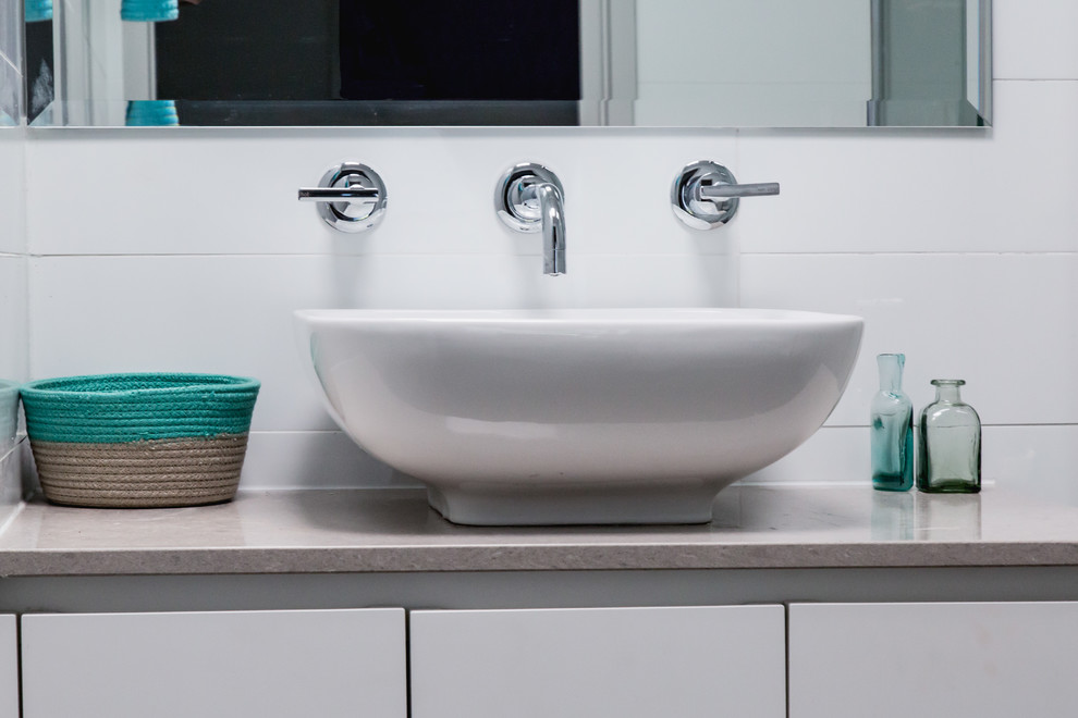 Foto de cuarto de baño actual con puertas de armario blancas, baldosas y/o azulejos blancos y lavabo sobreencimera