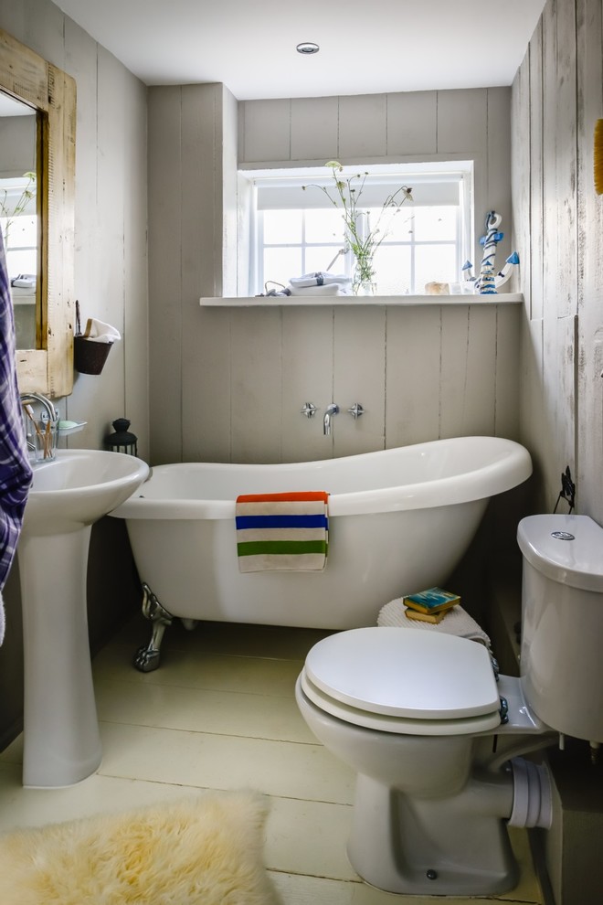 Foto de cuarto de baño infantil campestre pequeño con bañera con patas, sanitario de dos piezas, paredes grises, suelo de madera pintada, lavabo con pedestal y suelo beige