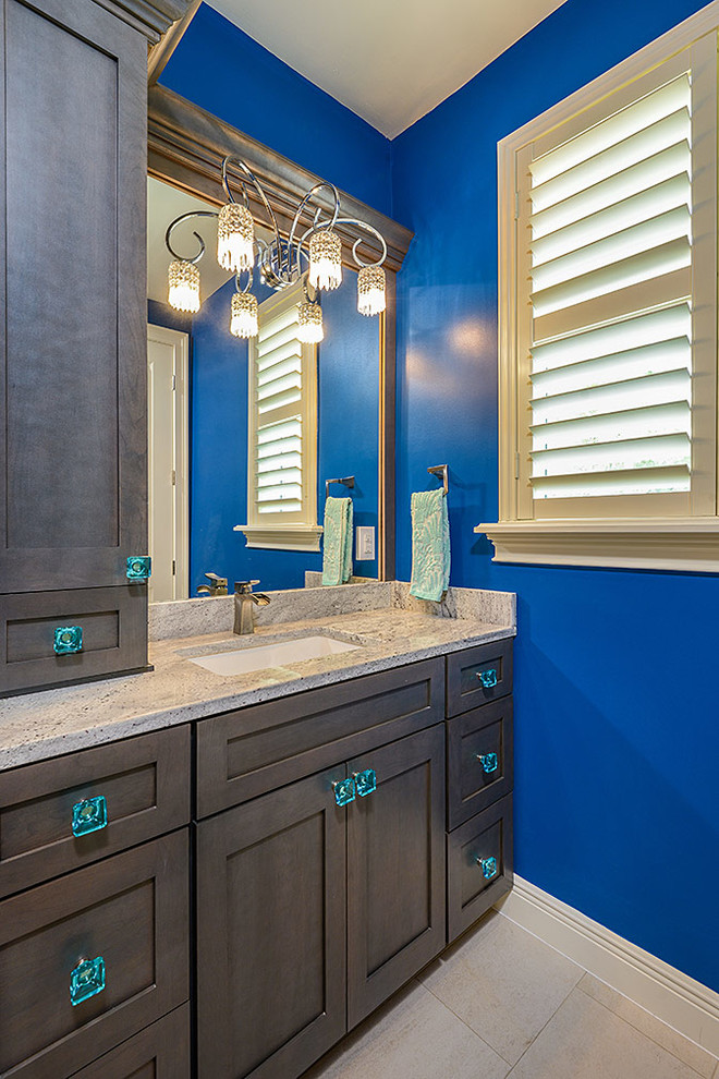 Exempel på ett mellanstort klassiskt badrum, med ett undermonterad handfat, skåp i shakerstil, skåp i mellenmörkt trä, granitbänkskiva, ett badkar i en alkov, en dusch/badkar-kombination, en toalettstol med hel cisternkåpa, beige kakel, porslinskakel, blå väggar och klinkergolv i porslin