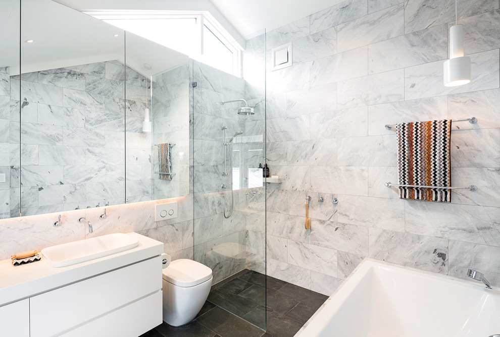 Inspiration för ett mellanstort funkis badrum, med släta luckor, vita skåp, ett platsbyggt badkar, en öppen dusch, en toalettstol med hel cisternkåpa, grå kakel, grå väggar, ett nedsänkt handfat och med dusch som är öppen