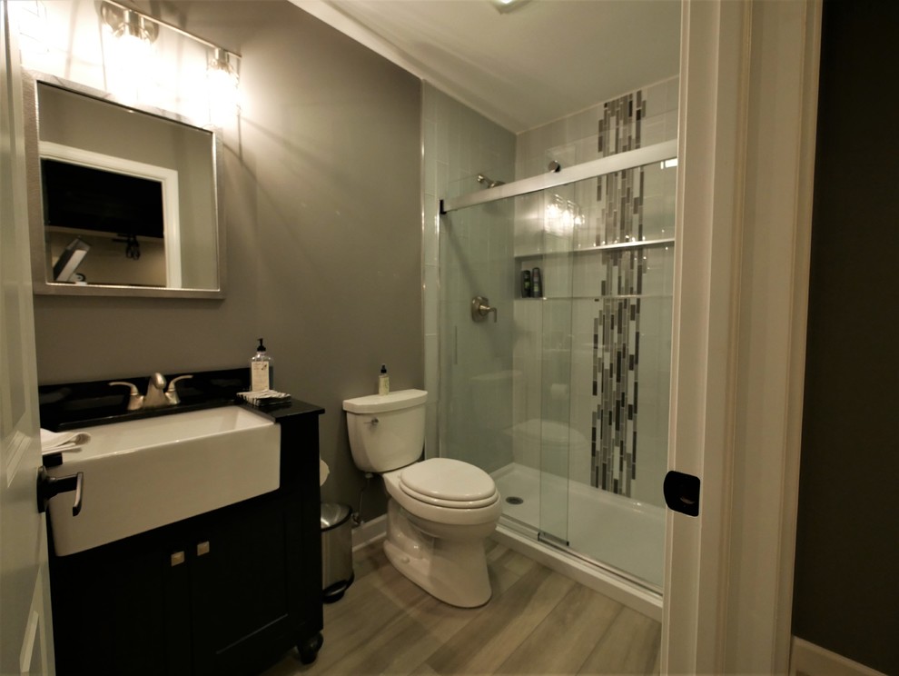 Photo of a medium sized classic shower room bathroom in Chicago with black cabinets, an alcove shower, a two-piece toilet, grey tiles, matchstick tiles, grey walls, laminate floors, tiled worktops, grey floors, a sliding door and black worktops.
