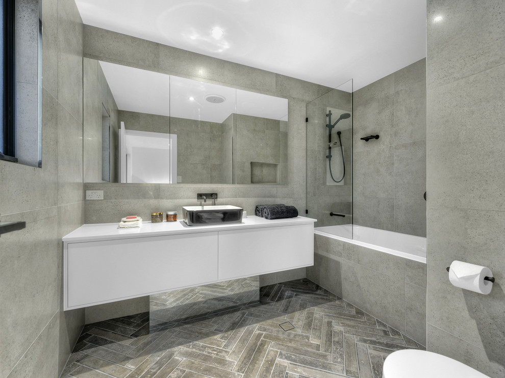 Photo of a medium sized urban bathroom in Brisbane with freestanding cabinets, white cabinets, grey tiles, porcelain tiles, a vessel sink and engineered stone worktops.