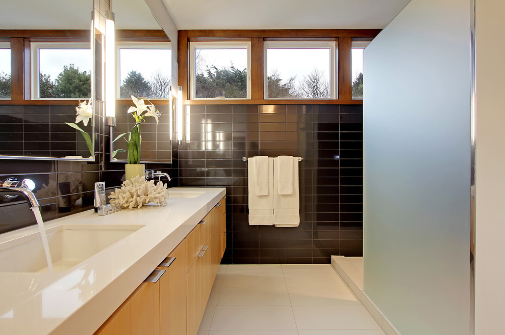 Cette image montre une salle de bain principale design en bois clair avec un placard à porte plane, un plan de toilette en quartz modifié, un carrelage noir, des carreaux de céramique, un mur blanc, un sol en carrelage de porcelaine, un lavabo encastré et une fenêtre.