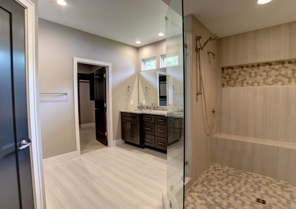 Example of a large trendy master beige tile laminate floor and beige floor corner shower design in Chicago with shaker cabinets, dark wood cabinets, beige walls, an undermount sink, granite countertops and a hinged shower door