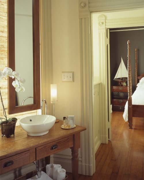 Idée de décoration pour une salle de bain principale bohème en bois brun de taille moyenne avec un placard sans porte, WC à poser, un mur blanc, un sol en bois brun, une vasque et un plan de toilette en bois.