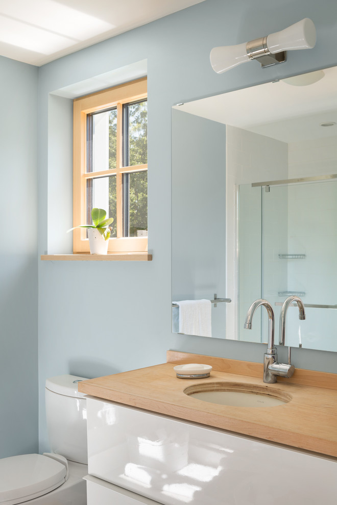 Exempel på ett mellanstort modernt badrum, med släta luckor, vita skåp, träbänkskiva och blå väggar