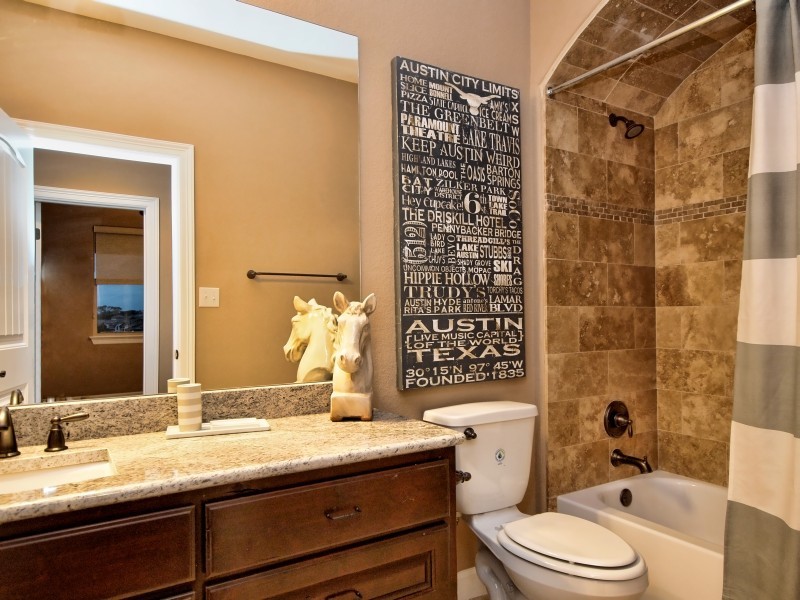 Bathroom - mid-sized traditional kids' beige tile and stone tile travertine floor bathroom idea in Austin with raised-panel cabinets, dark wood cabinets, granite countertops, an undermount sink and beige walls