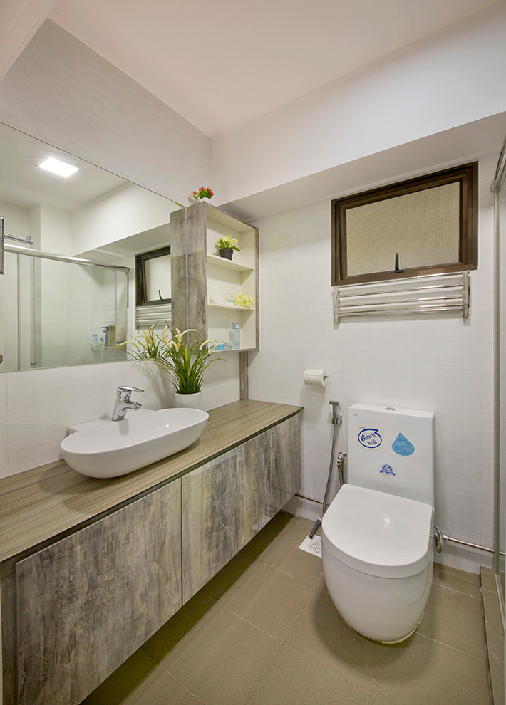 Cette photo montre une salle d'eau moderne en bois brun de taille moyenne avec un placard avec porte à panneau surélevé, un plan de toilette en bois, WC à poser, un carrelage gris, un mur blanc et un sol en ardoise.