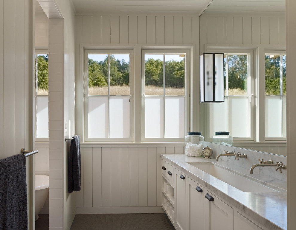 Example of a farmhouse bathroom design in San Francisco with marble countertops and a trough sink