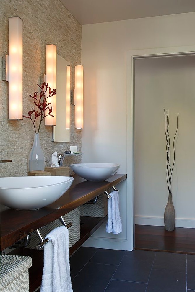 Example of a trendy beige tile bathroom design in San Francisco with a vessel sink, open cabinets, dark wood cabinets, wood countertops and white walls