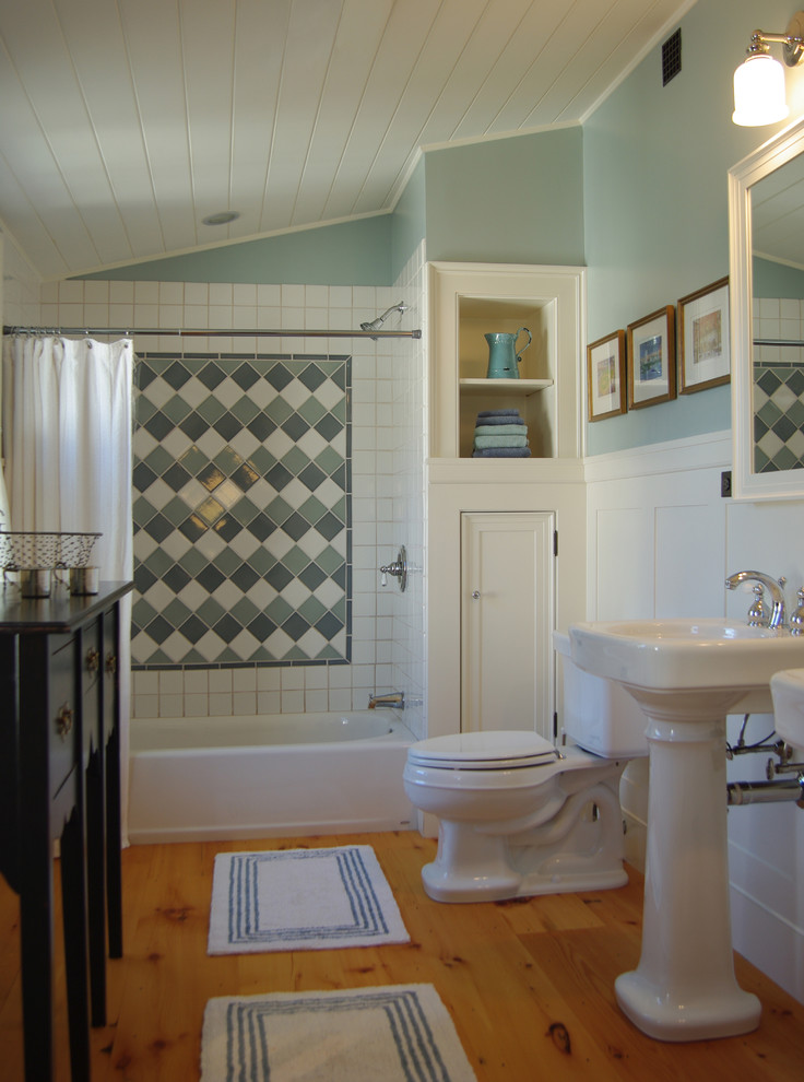 Bild på ett mellanstort vintage badrum, med luckor med infälld panel, vita skåp, ett badkar i en alkov, en dusch/badkar-kombination, en toalettstol med separat cisternkåpa, vit kakel, keramikplattor, gröna väggar, mellanmörkt trägolv, ett piedestal handfat, brunt golv och dusch med duschdraperi