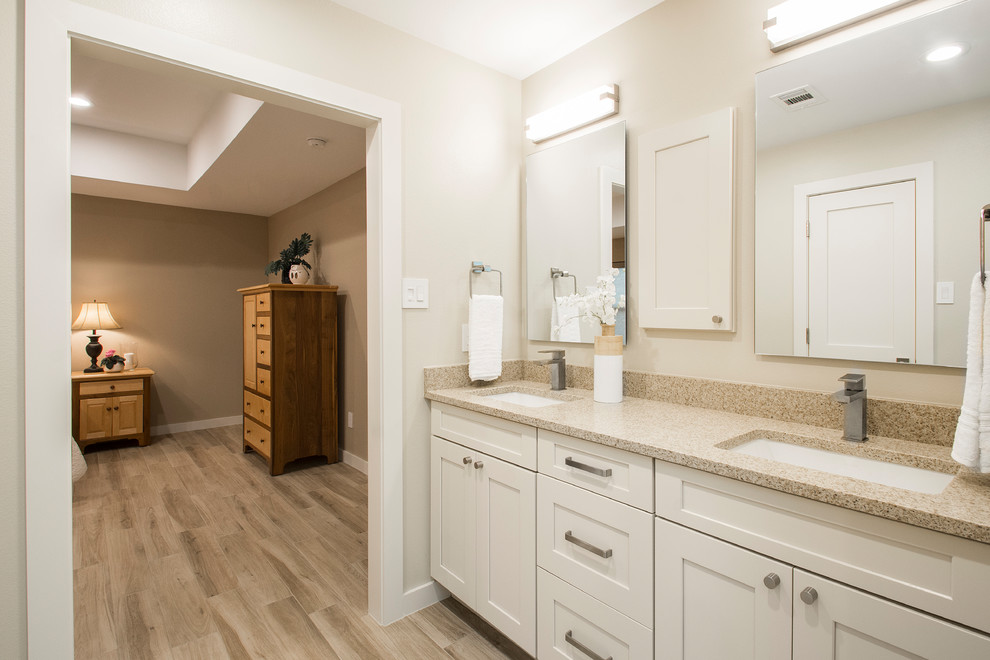 Large traditional ensuite bathroom in Dallas with beige walls, light hardwood flooring, beige floors, flat-panel cabinets, white cabinets, an alcove bath, a one-piece toilet, beige tiles, a submerged sink, engineered stone worktops and a hinged door.