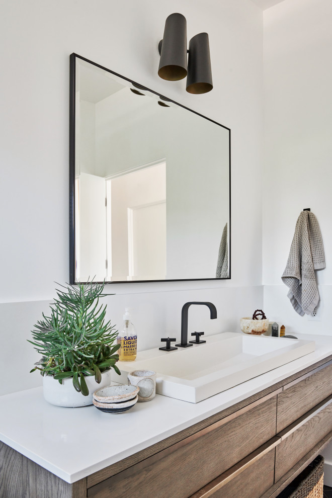Mid-sized trendy 3/4 white tile and ceramic tile ceramic tile and black floor alcove shower photo in Los Angeles with brown cabinets, a one-piece toilet, white walls, a drop-in sink, quartz countertops, a hinged shower door and white countertops