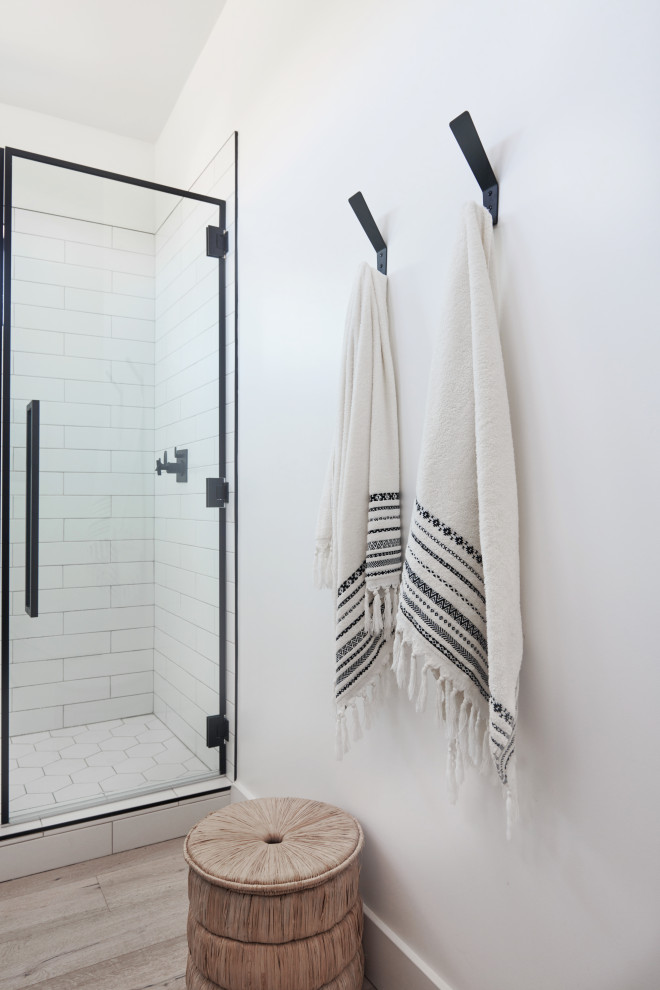 Example of a mid-sized trendy master white tile and subway tile light wood floor and brown floor alcove shower design in Los Angeles with brown cabinets, a one-piece toilet, white walls, an integrated sink, quartz countertops, a hinged shower door and white countertops