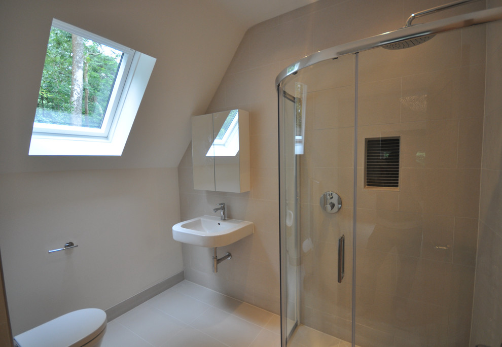 This is an example of a medium sized contemporary ensuite bathroom in Wiltshire with white cabinets, a walk-in shower, a wall mounted toilet, white tiles, porcelain tiles, white walls, porcelain flooring, a wall-mounted sink and tiled worktops.