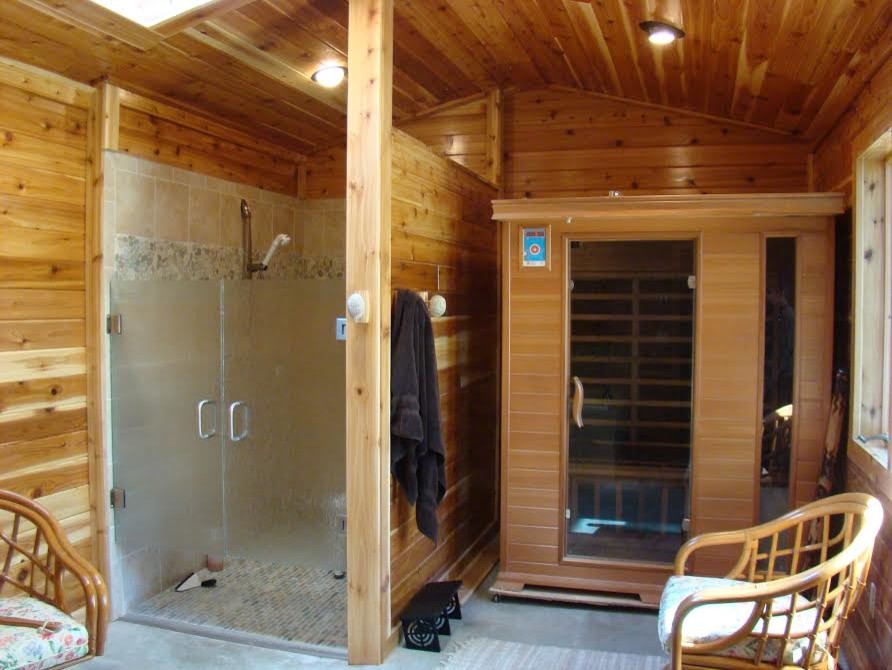 Ejemplo de sauna rústica grande con ducha empotrada, suelo de baldosas tipo guijarro, paredes marrones y ducha con puerta con bisagras