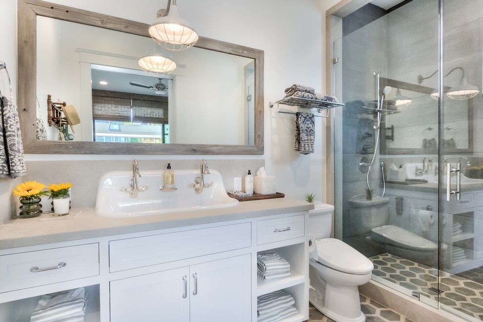 Foto på ett mellanstort lantligt badrum, med skåp i shakerstil, vita skåp, en dusch i en alkov, grå kakel, porslinskakel, vita väggar, cementgolv, ett nedsänkt handfat, flerfärgat golv och dusch med gångjärnsdörr
