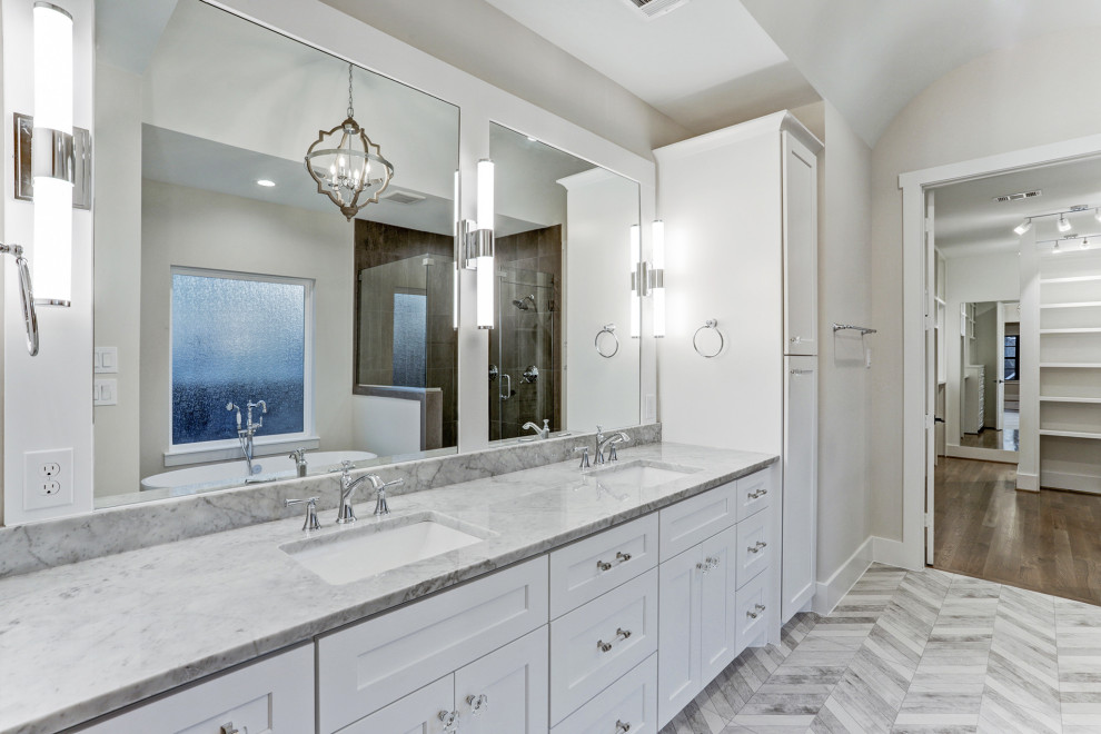 Photo of a large classic bathroom in Houston with shaker cabinets, white cabinets, a freestanding bath, a corner shower, porcelain tiles, white walls, porcelain flooring, a submerged sink, marble worktops, grey floors and grey worktops.