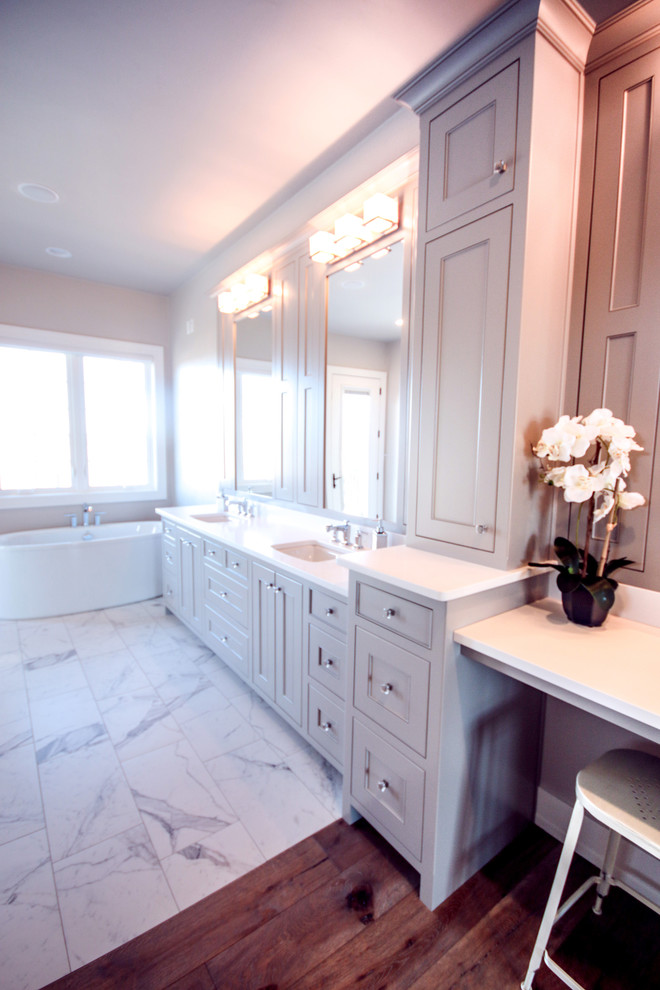 Klassisk inredning av ett stort en-suite badrum, med ett undermonterad handfat, skåp i shakerstil, vita skåp, bänkskiva i kvarts, ett hörnbadkar, vita väggar och klinkergolv i keramik