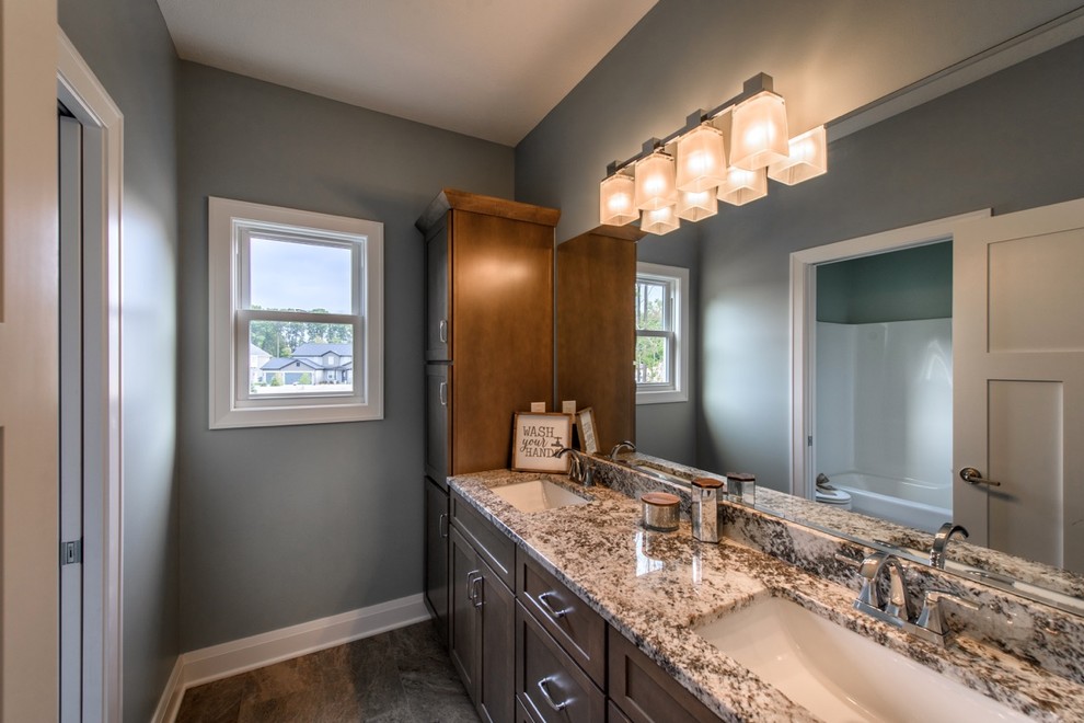 Example of a small arts and crafts master gray tile medium tone wood floor and brown floor bathroom design in Cleveland with brown cabinets, blue walls, a drop-in sink and granite countertops