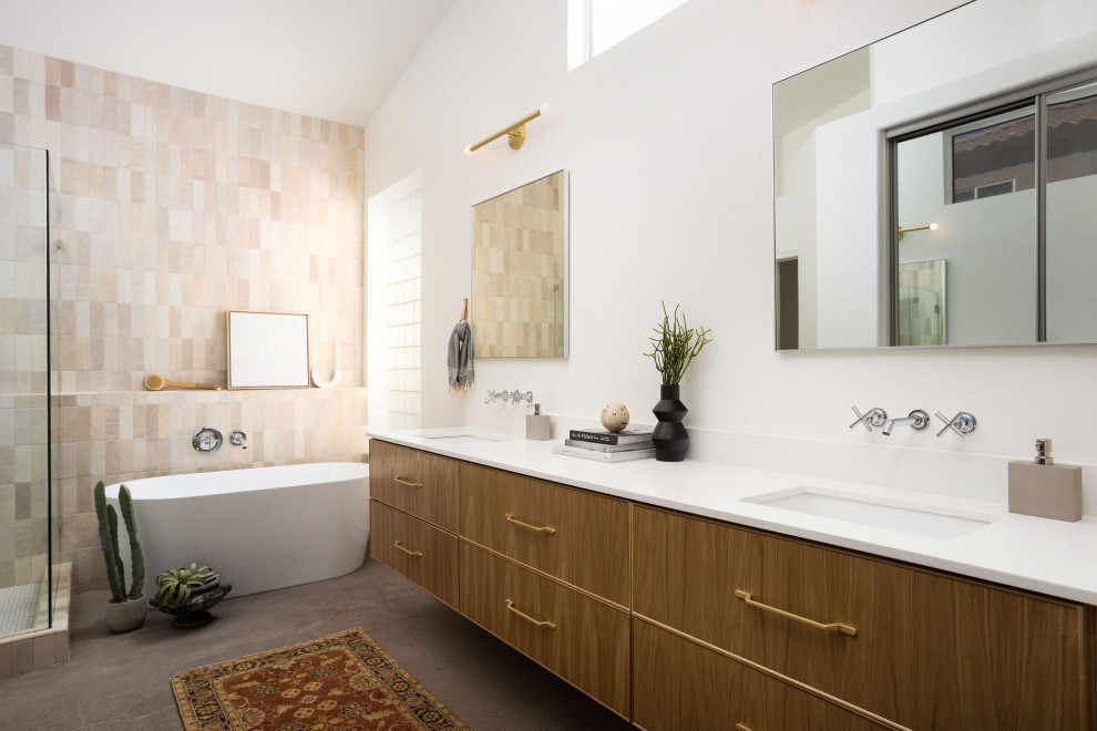 На фото: главная ванная комната среднего размера в скандинавском стиле с плоскими фасадами, светлыми деревянными фасадами, отдельно стоящей ванной, угловым душем, раздельным унитазом, бежевой плиткой, керамической плиткой, белыми стенами, бетонным полом, врезной раковиной, столешницей из искусственного кварца, душем с распашными дверями, белой столешницей, тумбой под две раковины и подвесной тумбой