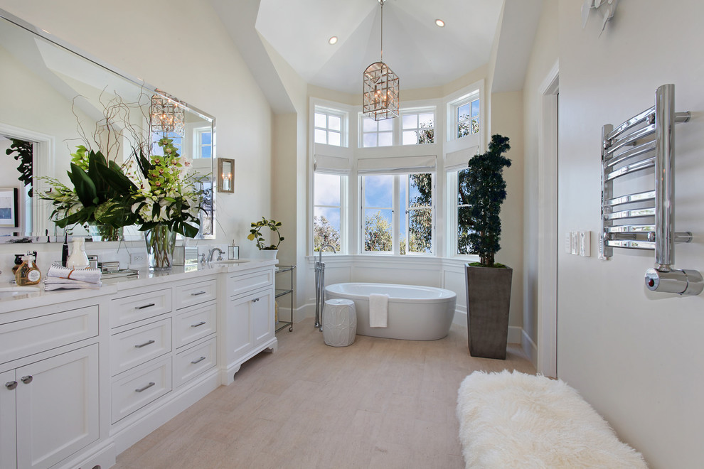 Foto de cuarto de baño marinero con lavabo bajoencimera, armarios estilo shaker, puertas de armario blancas, bañera exenta, paredes blancas y suelo de madera clara
