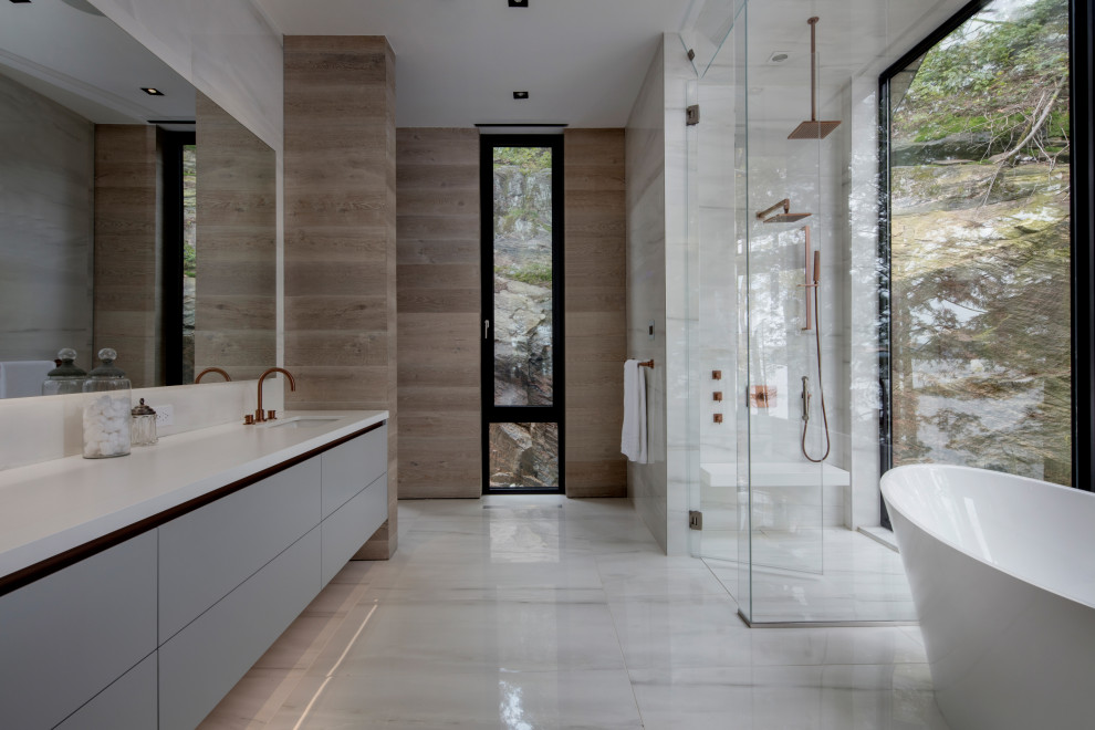 Photo of a contemporary ensuite bathroom in Toronto with flat-panel cabinets, grey cabinets, a freestanding bath, a built-in shower, white tiles, a submerged sink, white floors, a hinged door, white worktops, double sinks, a floating vanity unit and wood walls.