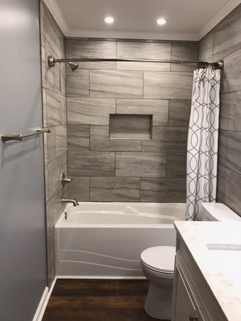 Medium sized traditional shower room bathroom in Other with white cabinets, a shower/bath combination, a one-piece toilet, grey tiles, ceramic tiles, grey walls, a submerged sink, engineered stone worktops, a shower curtain, recessed-panel cabinets, an alcove bath, dark hardwood flooring and brown floors.