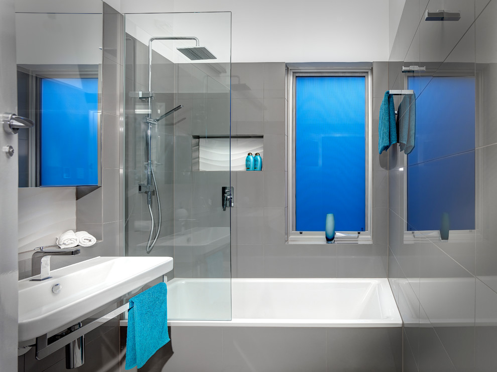Ejemplo de cuarto de baño contemporáneo pequeño con bañera encastrada, combinación de ducha y bañera, sanitario de pared, baldosas y/o azulejos grises, baldosas y/o azulejos de porcelana, paredes blancas y suelo de mármol