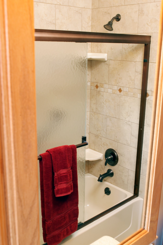Kleines Uriges Duschbad mit Kassettenfronten, hellen Holzschränken, Duschbadewanne, weißer Wandfarbe, Travertin, integriertem Waschbecken und Mineralwerkstoff-Waschtisch in Cincinnati