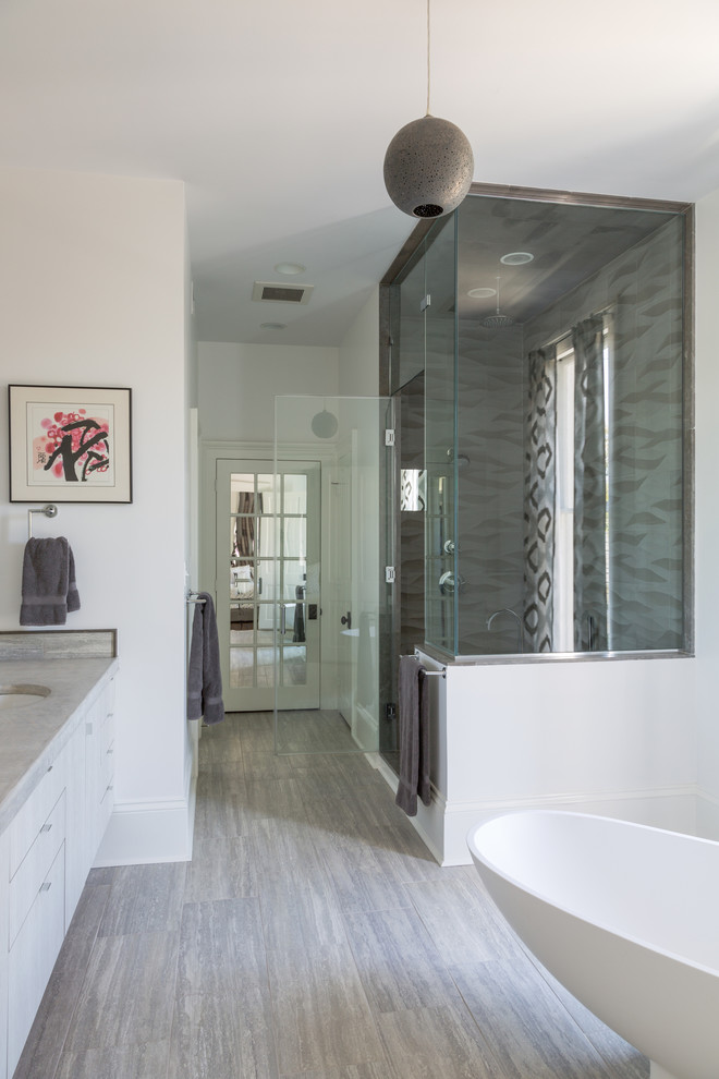 Inspiration for a medium sized traditional ensuite bathroom in New Orleans with flat-panel cabinets, limestone worktops, a freestanding bath, a corner shower, a two-piece toilet, white walls, lino flooring, a submerged sink and grey cabinets.