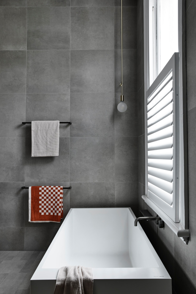 Idéer för att renovera ett funkis grå grått en-suite badrum, med grå skåp, ett fristående badkar, en öppen dusch, en vägghängd toalettstol, grå kakel, stenkakel, grå väggar, ett fristående handfat, marmorbänkskiva, grått golv och med dusch som är öppen