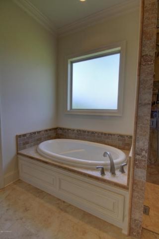 This is an example of a large traditional ensuite bathroom in New Orleans with a built-in bath, grey tiles, stone tiles, beige walls, ceramic flooring, a submerged sink and granite worktops.