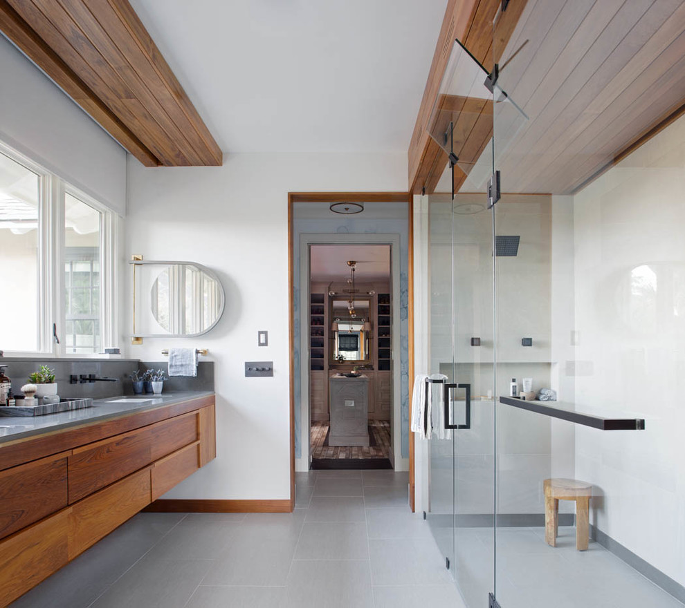 Ejemplo de cuarto de baño principal, contemporáneo, grande, con lavabo bajoencimera, armarios con paneles lisos, puertas de armario de madera oscura, ducha a ras de suelo, paredes blancas, suelo de baldosas de porcelana, encimera de cuarzo compacto, suelo gris, ducha con puerta con bisagras y vestidor