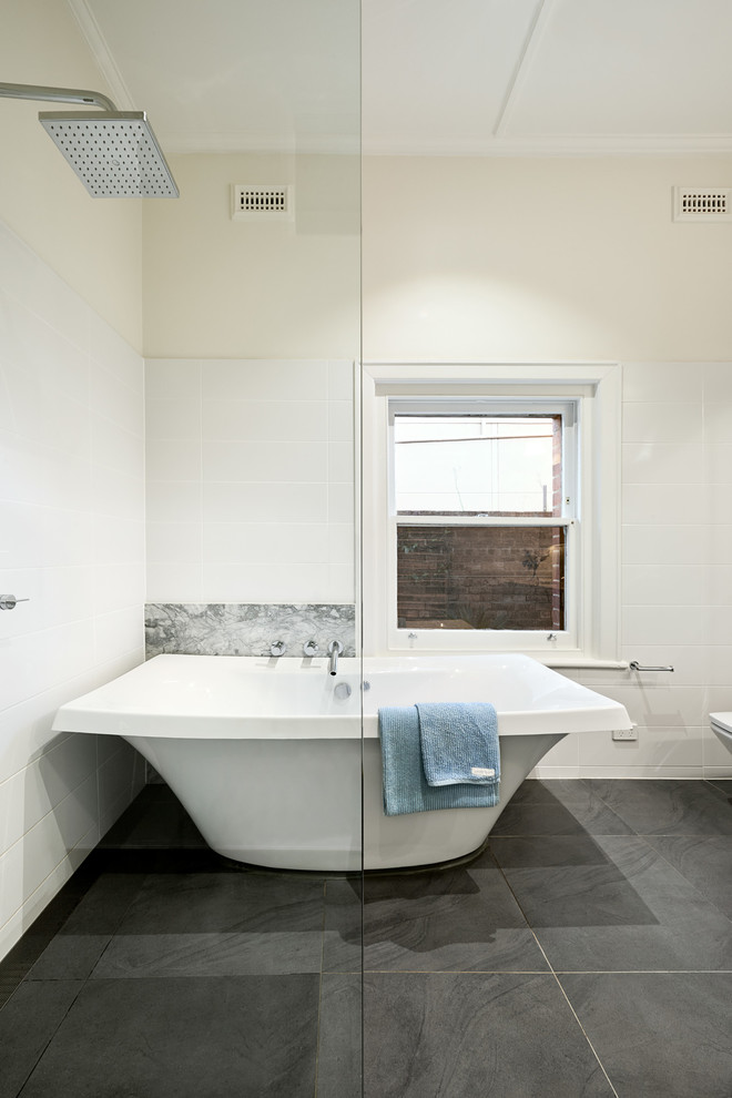 Immagine di una stanza da bagno design con vasca freestanding, pareti bianche, piastrelle in ceramica e pavimento con piastrelle in ceramica