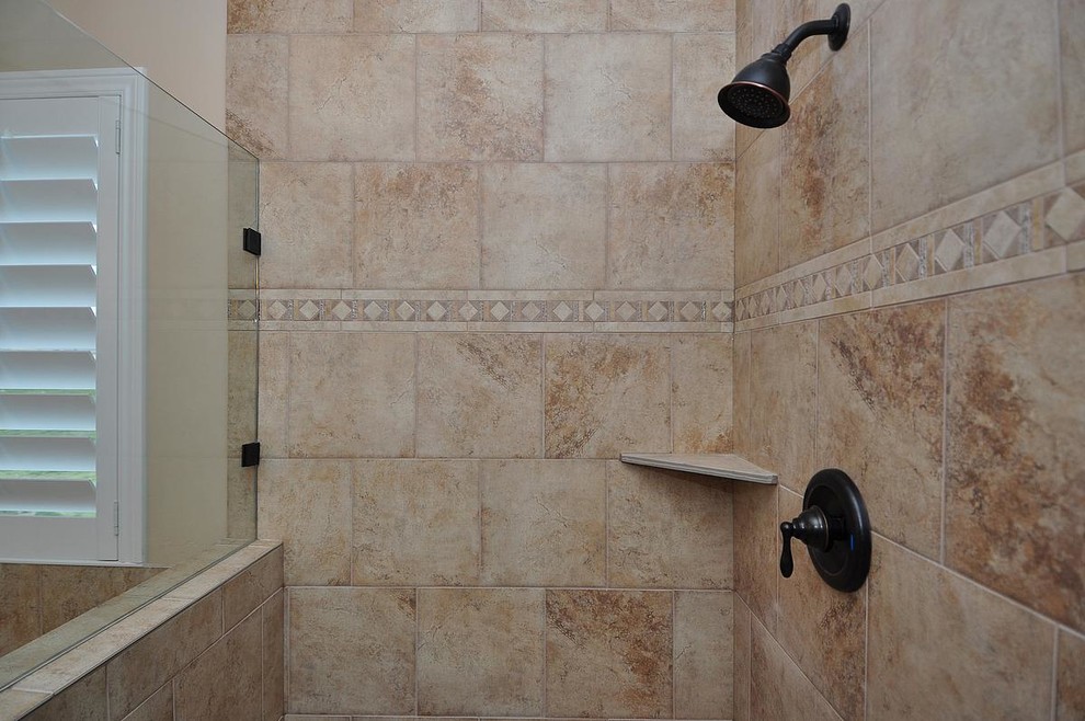 Bild på ett mellanstort amerikanskt en-suite badrum, med luckor med upphöjd panel, skåp i mörkt trä, ett platsbyggt badkar, en kantlös dusch, en vägghängd toalettstol, brun kakel, keramikplattor, beige väggar, klinkergolv i keramik, ett undermonterad handfat och marmorbänkskiva