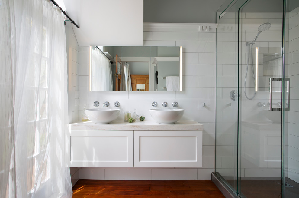 Foto på ett lantligt badrum med dusch, med en dusch i en alkov, vit kakel, grå väggar och ett fristående handfat