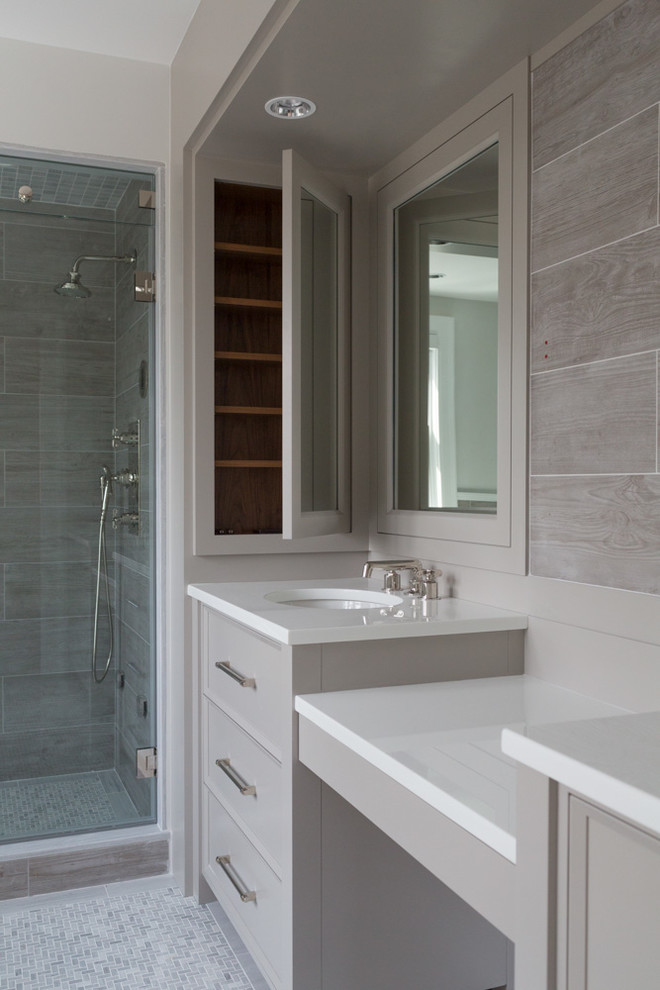 На фото: большая главная ванная комната в стиле неоклассика (современная классика) с плоскими фасадами, серыми фасадами, отдельно стоящей ванной, душем в нише, унитазом-моноблоком, серой плиткой, керамической плиткой, мраморным полом, врезной раковиной, стеклянной столешницей, серым полом и душем с распашными дверями
