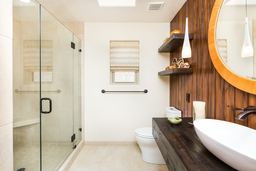 Cette image montre une salle de bain sud-ouest américain en bois foncé de taille moyenne avec une vasque, un plan de toilette en bois, WC à poser, un carrelage beige, des carreaux de porcelaine, un mur beige et un sol en carrelage de porcelaine.