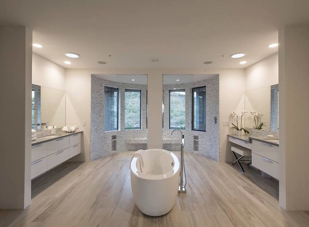 Стильный дизайн: большая главная ванная комната в современном стиле с плоскими фасадами, белыми фасадами, отдельно стоящей ванной, двойным душем, белыми стенами, полом из ламината, врезной раковиной, бежевым полом, открытым душем, серой плиткой и каменной плиткой - последний тренд