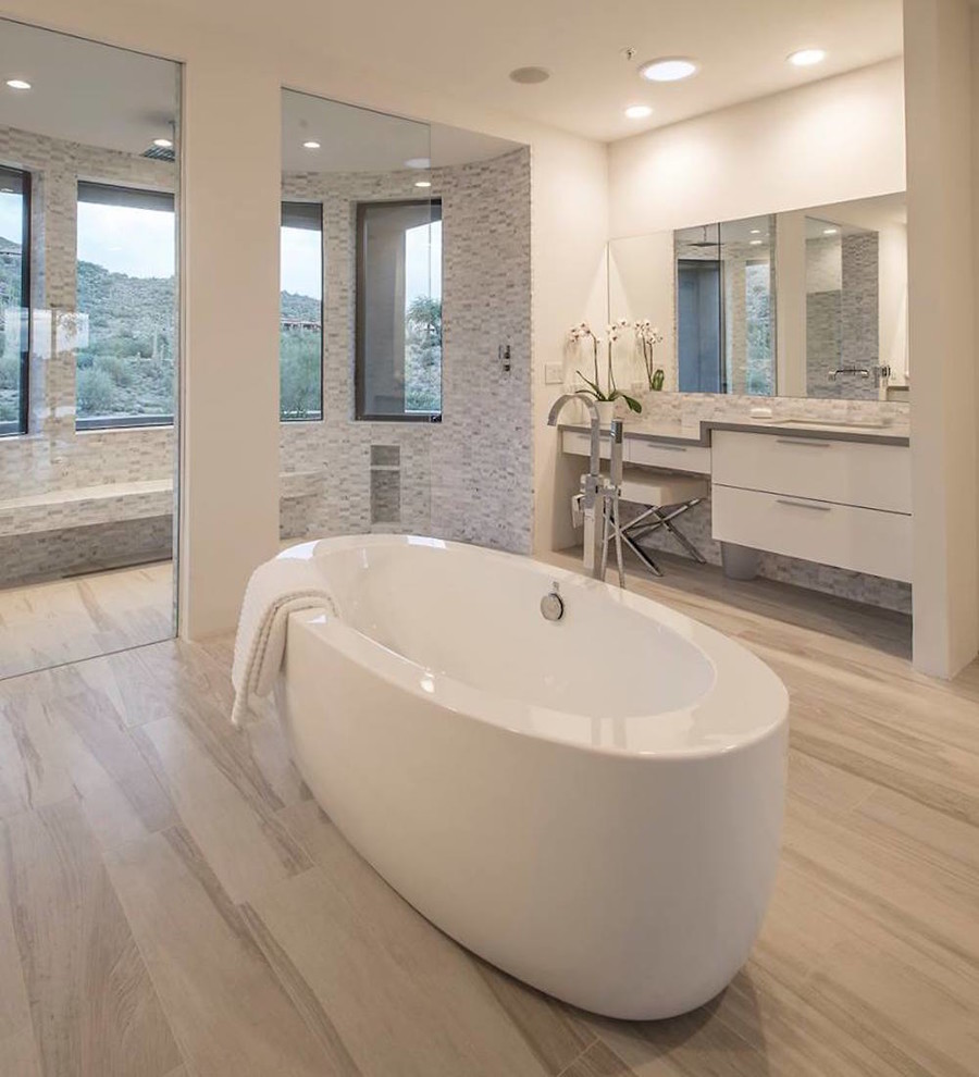 На фото: большая главная ванная комната в современном стиле с плоскими фасадами, белыми фасадами, отдельно стоящей ванной, душем в нише, белыми стенами, полом из ламината, врезной раковиной, бежевым полом, открытым душем, серой плиткой и удлиненной плиткой