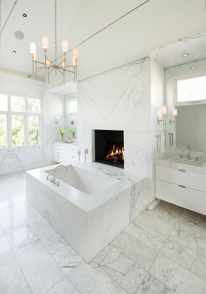Inspiration pour une grande salle de bain principale design avec un placard à porte plane, des portes de placard blanches, une baignoire encastrée, un carrelage gris, du carrelage en marbre, un sol en marbre, un lavabo encastré, un plan de toilette en marbre et un sol gris.