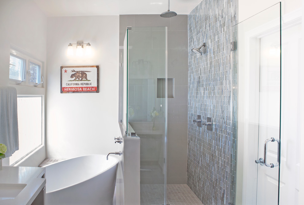 Aménagement d'une salle de bain classique en bois brun avec un placard à porte plane, une baignoire indépendante, une douche d'angle, un carrelage bleu, des plaques de verre, un mur blanc, un sol en carrelage de porcelaine, un lavabo encastré et un plan de toilette en quartz modifié.