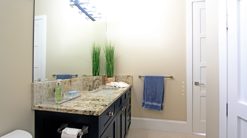 Example of a minimalist ceramic tile bathroom design in Miami with shaker cabinets and granite countertops