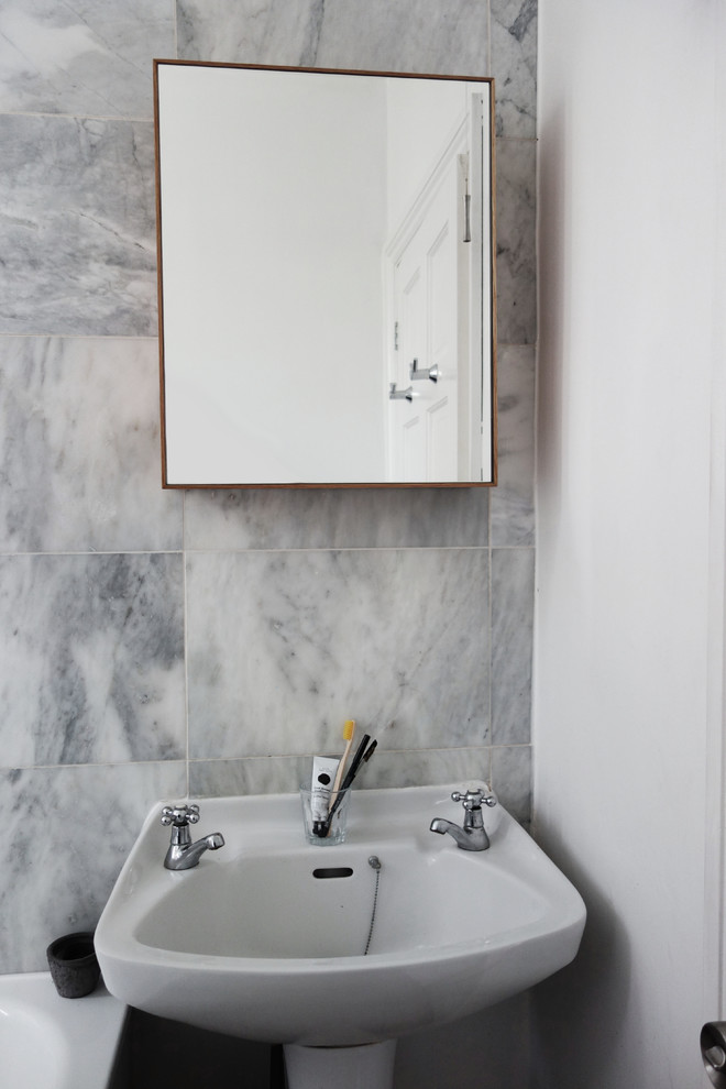 Example of a small minimalist kids' gray tile and stone slab light wood floor bathroom design in London with a pedestal sink, glass-front cabinets, medium tone wood cabinets, a two-piece toilet and white walls
