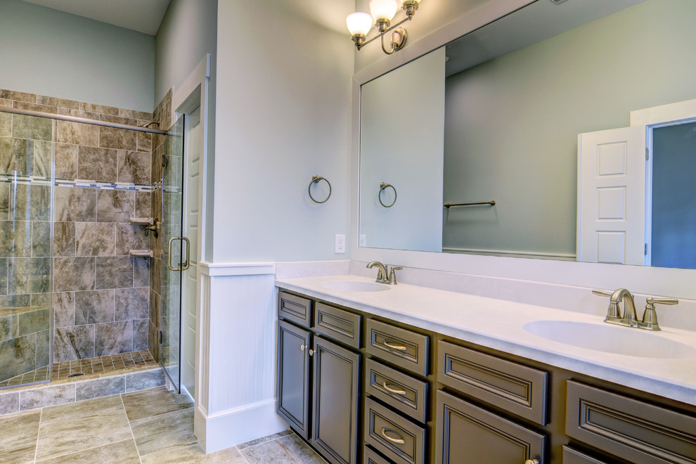 Foto di una stanza da bagno padronale stile marino di medie dimensioni con lavabo integrato, ante con riquadro incassato, ante grigie, top in superficie solida, vasca da incasso, piastrelle grigie, pareti blu e doccia alcova