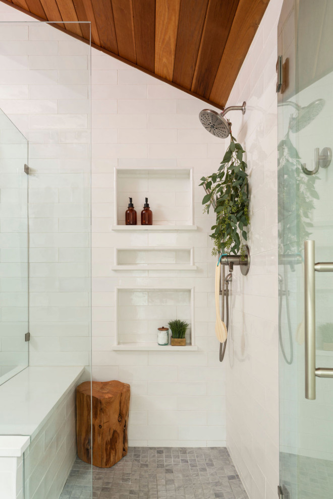 На фото: главная ванная комната среднего размера в стиле ретро с плоскими фасадами, светлыми деревянными фасадами, отдельно стоящей ванной, угловым душем, белой плиткой, керамической плиткой, белыми стенами, полом из керамогранита, врезной раковиной, столешницей из искусственного кварца, серым полом, душем с распашными дверями, белой столешницей, нишей, тумбой под две раковины, встроенной тумбой и деревянным потолком с