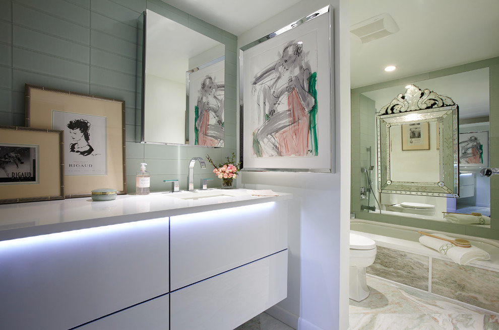 Immagine di una piccola stanza da bagno padronale minimalista con lavabo sottopiano, ante lisce, ante bianche, vasca sottopiano, WC a due pezzi, piastrelle verdi, piastrelle di vetro, pareti bianche e pavimento in marmo